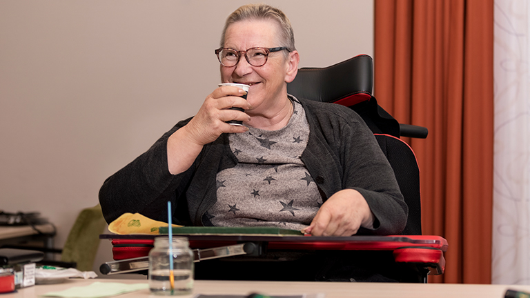 Vrouw lacht en drinkt uit kartonnen beker